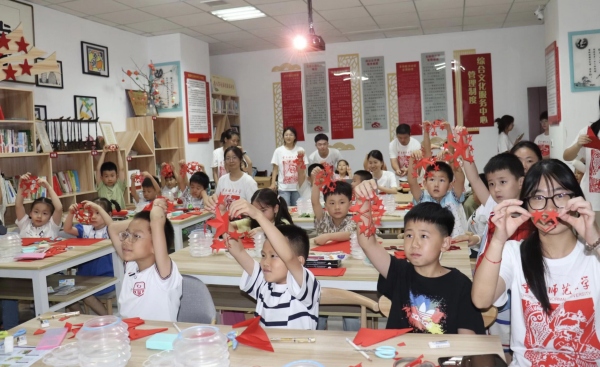 实践团成员与孩子们共同创作剪纸作品。外围买球的app十大平台美术学院供图